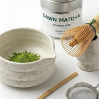 Matcha tea set with bowl, whisk, and container on a white background
