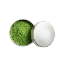 Open container of green powder on a white background